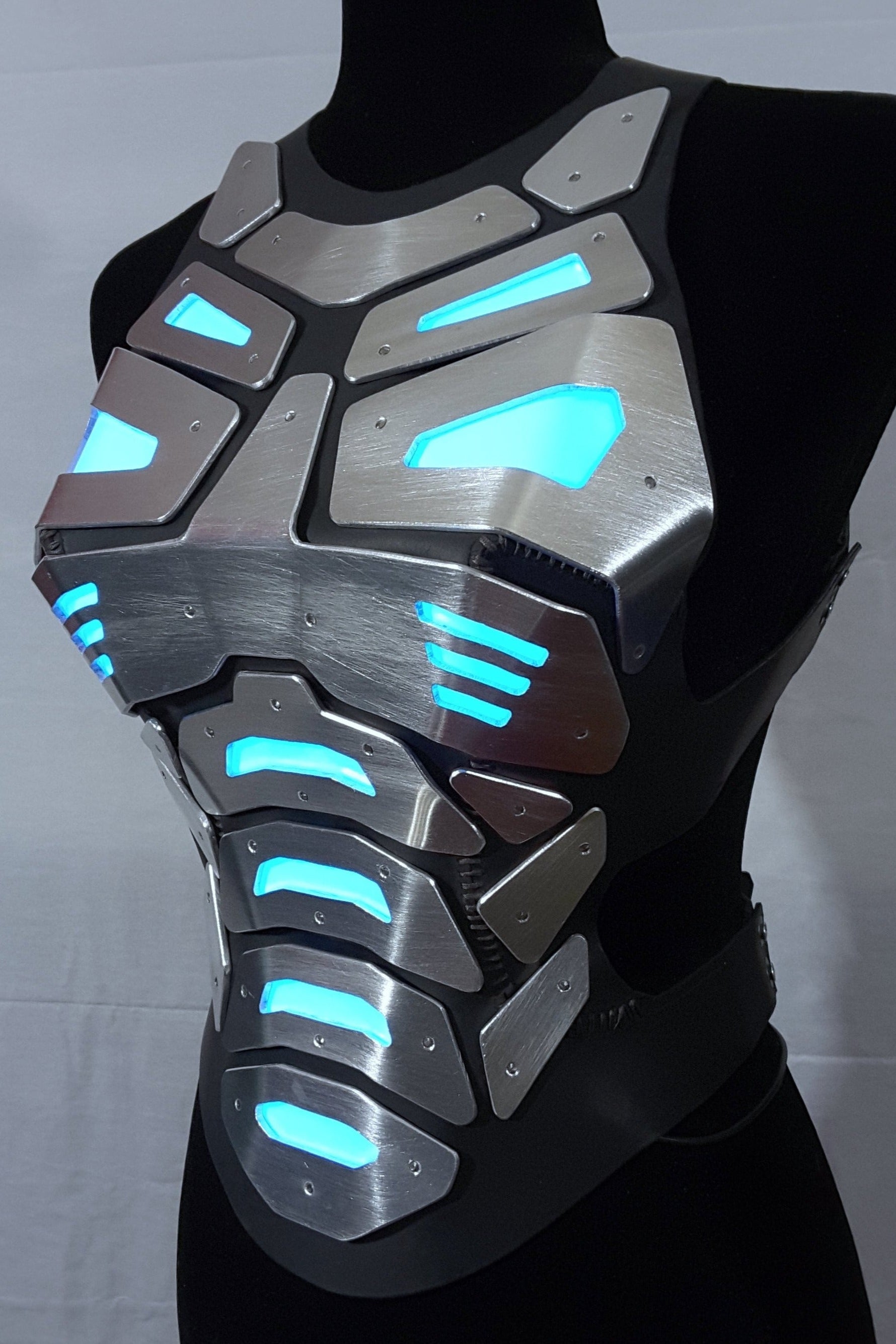 Mannequin wearing futuristic torso armor in silver and black with glowing blue lights